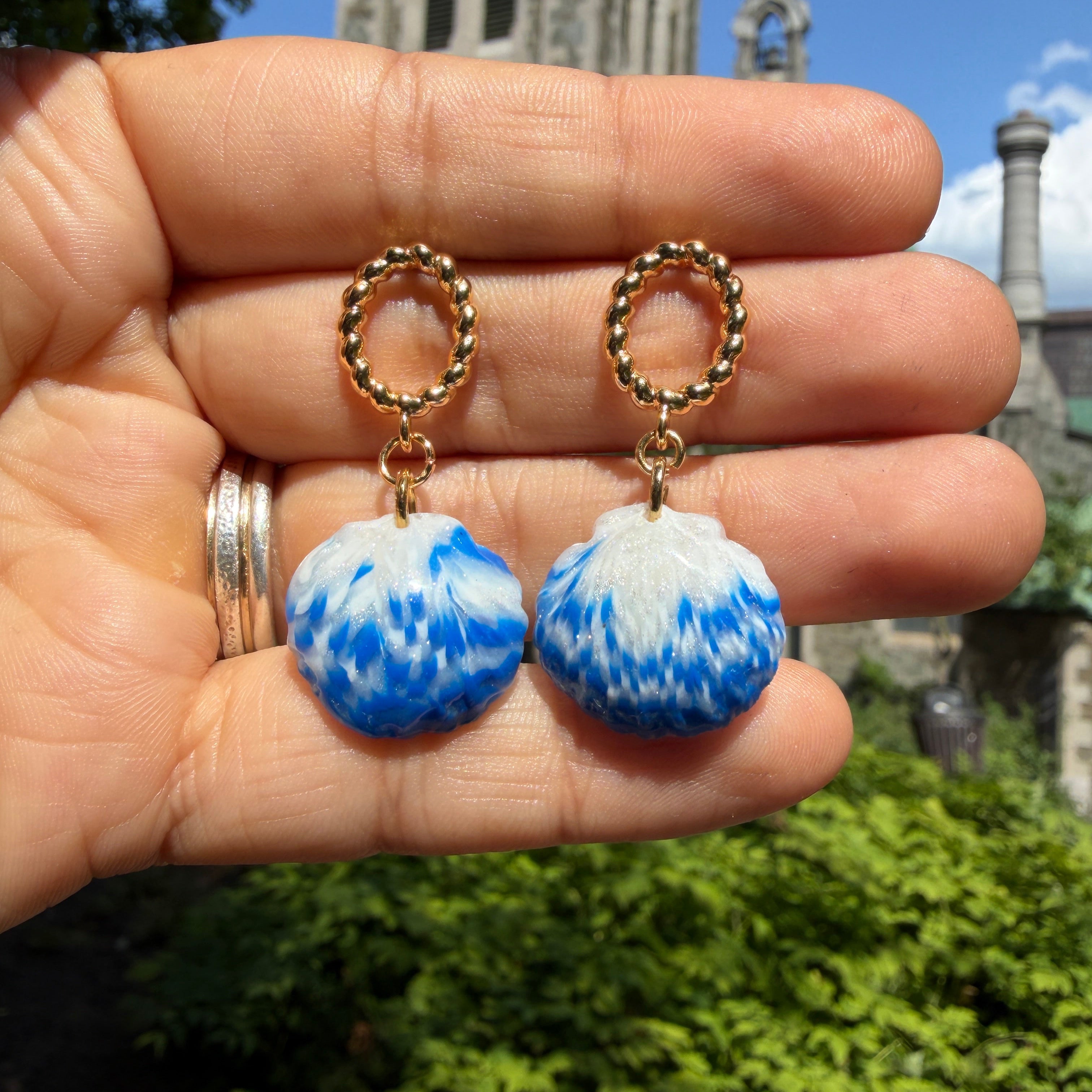 Boucles d’oreilles Galite – Perle d’écume : paire Galite tenue dans la main devant un jardin