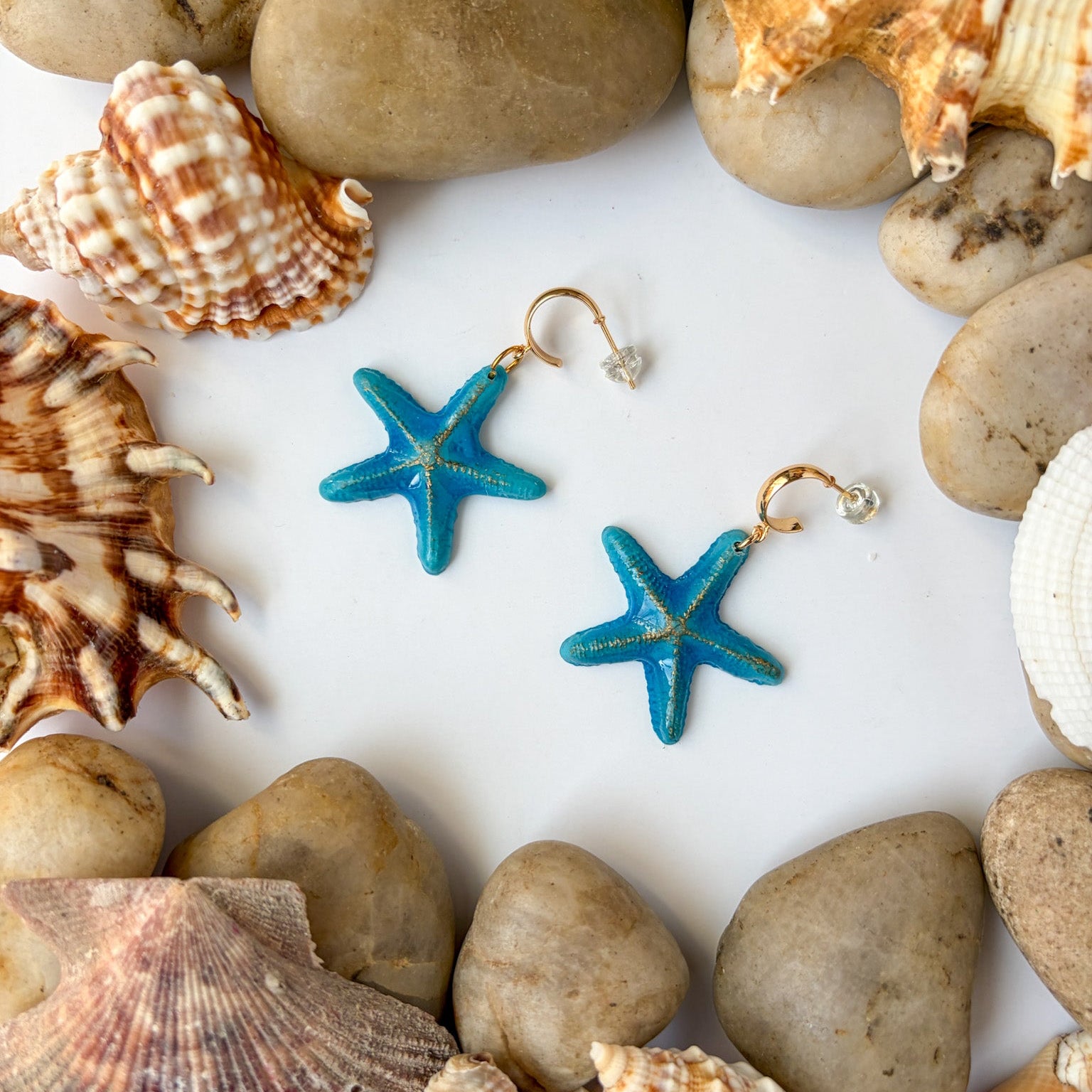 Boucles d’oreilles Étoiles de mer sculptées : étoiles de mer bleu turquoise posées parmi coquillages et galets