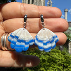 Boucles d’oreilles Laguna – Coquillage sculpté : coquillages rayés bleu et blanc sur attaches argentées, tenus dans la main