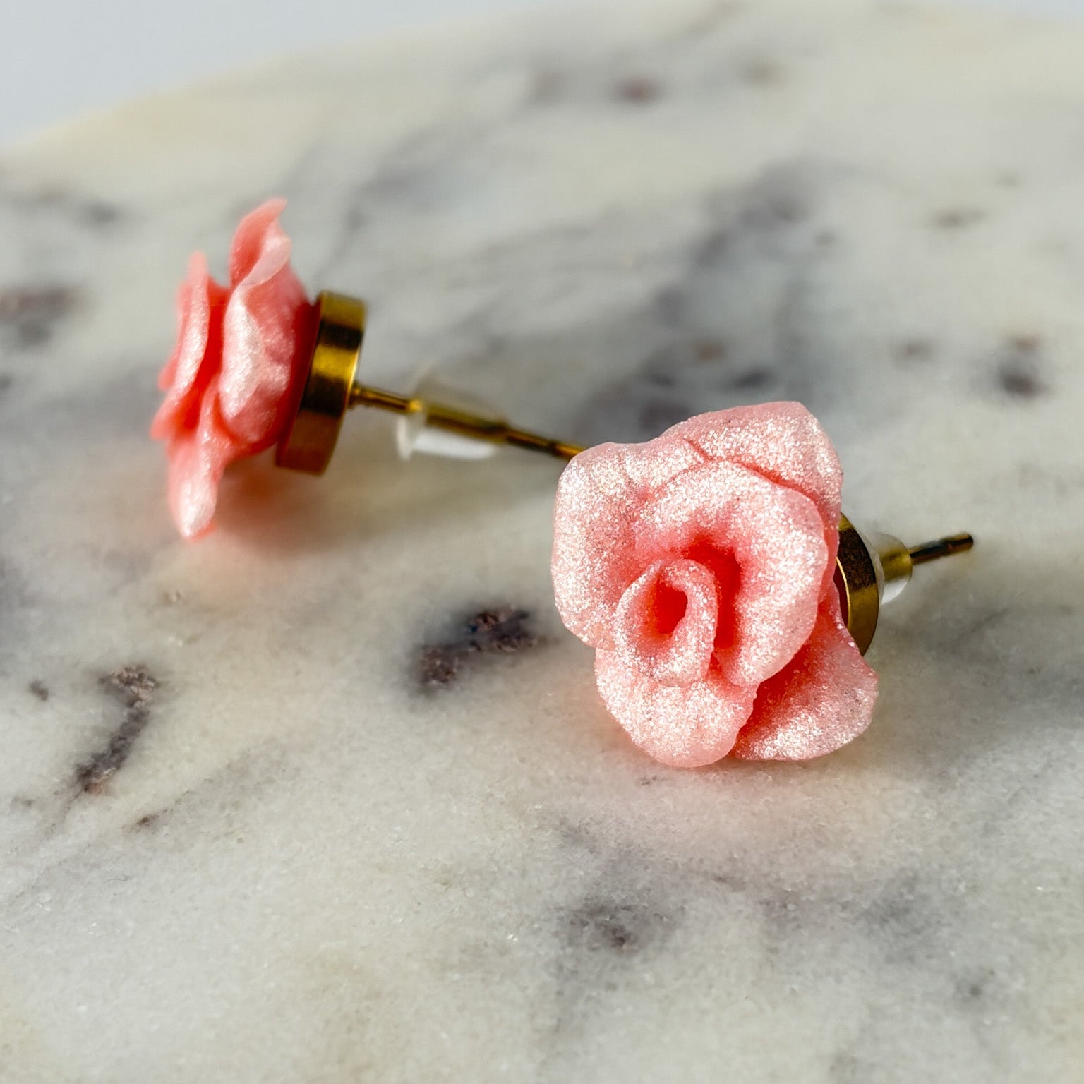 Boucles d’oreilles Roses Passion – Rose poudre métallique : roses rose poudre métallisées, vue de face et de profil sur marbre