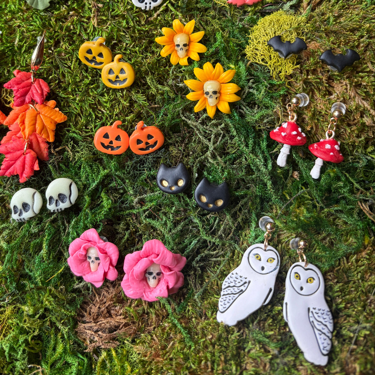 Bijoux d’Halloween en argile polymère sur la mousse, avec des puces chats noirs aux yeux dorés.