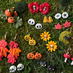 Sélection de bijoux d’automne et d’Halloween sur fond de mousse, dont les citrouilles orange sur feuillage vert du modèle Potager enchanté.