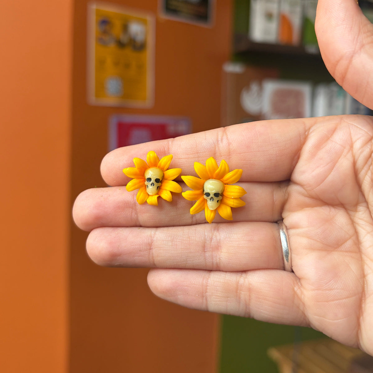 Puces tournesols jaunes avec petits crânes ivoire au centre, présentées dans une main.