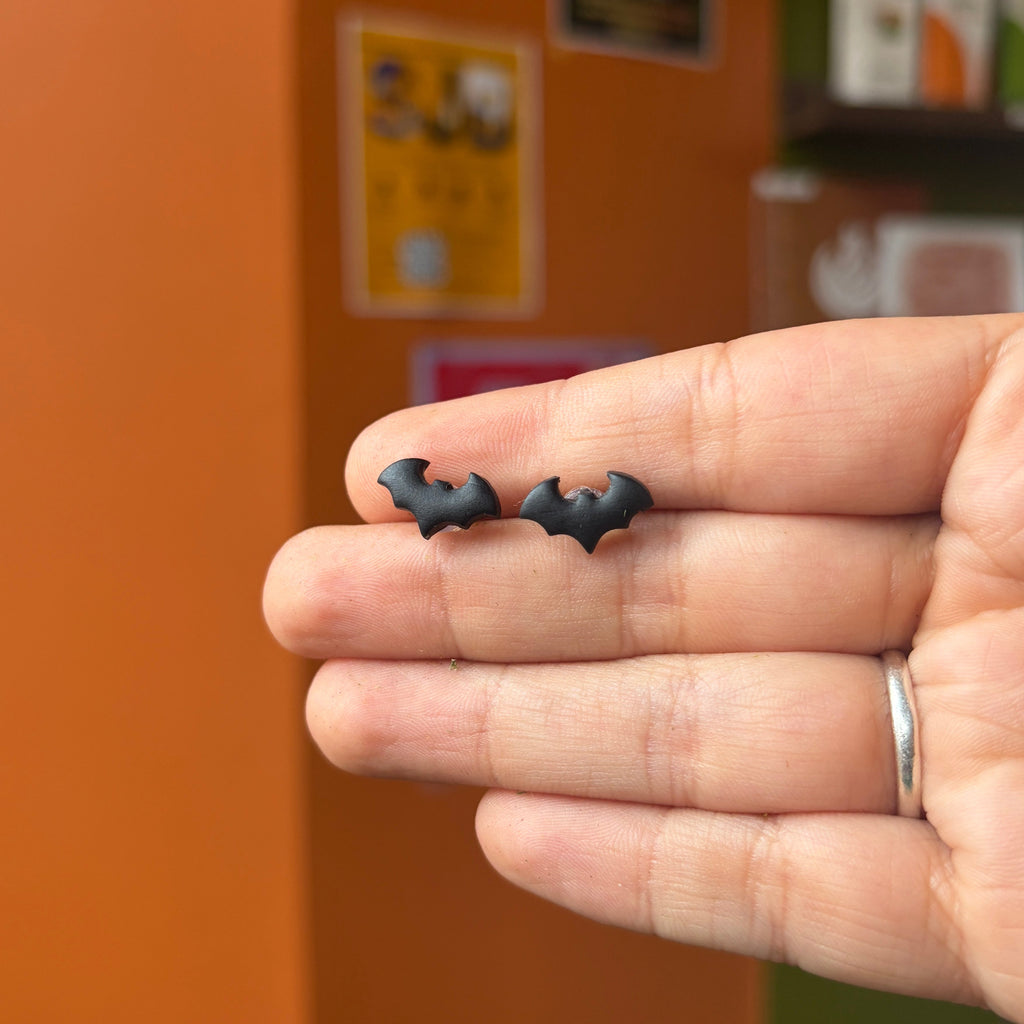 Paire de puces chauves-souris noires en argile polymère présentée dans une main.