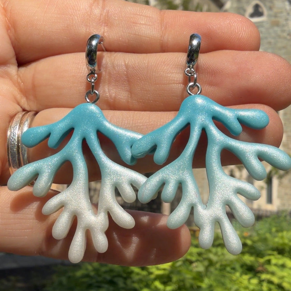 Boucles d’oreilles Coraux Morjane : branches de corail dégradées du bleu au blanc, tenues dans la main